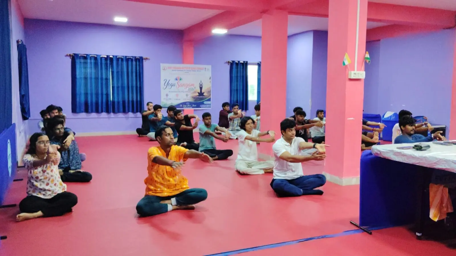 Students and faculty performing seated yoga stretches on the floor at SVIST during the International Yoga Day, Yoga Sangam 2026 celebration