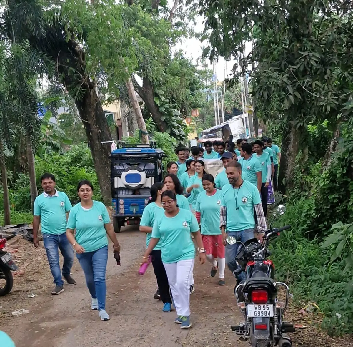 Faculty, staff and students of SVIST in matching teal t-shirts walking along a tree-lined campus road during the Annual Walkathon 2026, part of the Yoga Sangam celebration