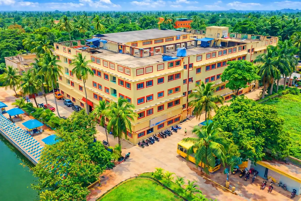 Drone view of the SVIST engineering college campus at Sonarpur, South Kolkata, showing the academic block, lakeside amphitheatre seating, greenery and college bus